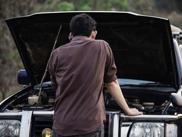 Ein Mann steht vor seinem Unfallwagen und macht sich Sorgen, was er damit anfangen soll